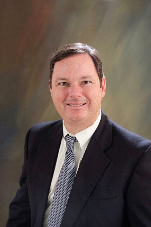 A man in a suit and tie is smiling for the camera.